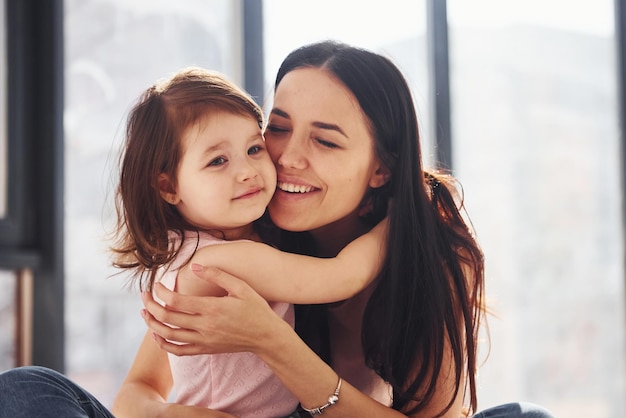 Jeune mère avec sa fille s'embrassant sur le lit