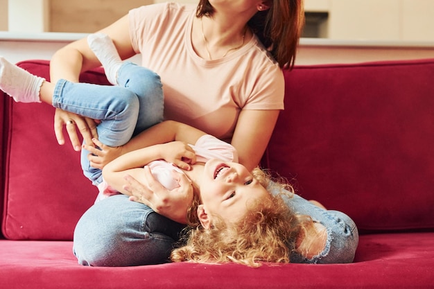 Jeune mère avec sa petite fille dans des vêtements décontractés ensemble à l'intérieur à la maison