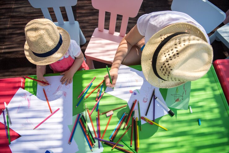 une jeune mère et sa petite fille passent joyeusement du temps ensemble à l'aide de crayons de couleur tout en dessinant des images colorées dans l'école maternelle extérieure