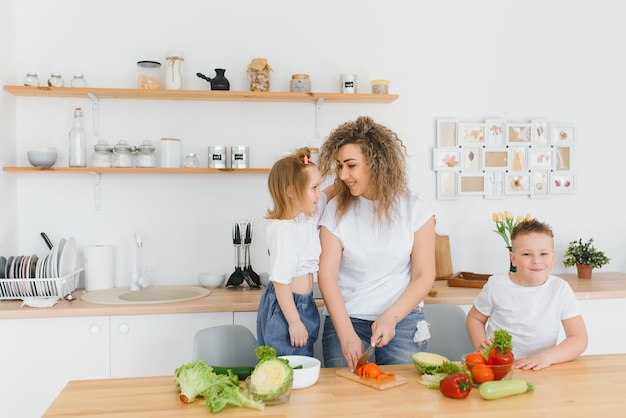 Jeune mère et ses deux enfants faisant une salade de légumes