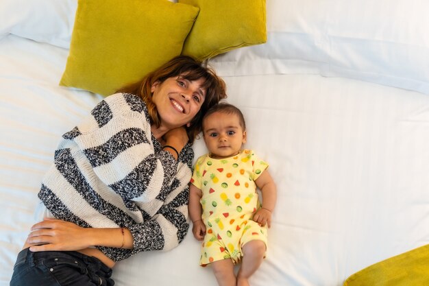 Jeune mère avec son bébé sur le lit dans sa chambre, portrait de mode de vie d'une jeune mère, famille à la maison