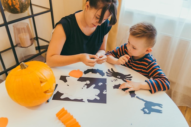 Jeune mère avec son petit garçon faisant des araignées artisanales pour les vacances d'halloween