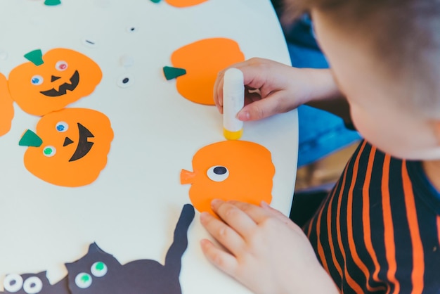 Jeune mère avec son petit garçon faisant des citrouilles artisanales pour les vacances d'halloween