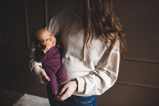 Jeune mère tenant un enfant nouveau-né allongé sur les mains dans la chambre à la maison Concept de mode de vie familial Maternité