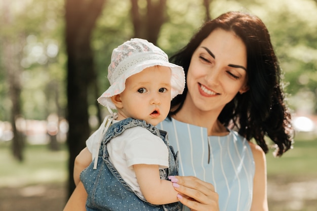 Une jeune mère tient la petite fille dans le parc en été