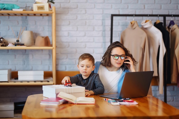 Jeune mère travaille avec un petit garçon Femme d'affaires parlant au téléphone et discutant de problèmes de travail