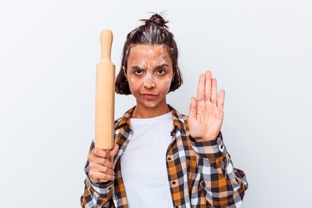 Jeune métisse femme faisant du pain isolé sur mur blanc debout avec la main tendue montrant le panneau d'arrêt, vous empêchant.