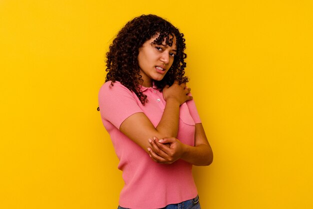 Jeune métisse femme isolée sur fond jaune massant le coude, souffrant après un mauvais mouvement.