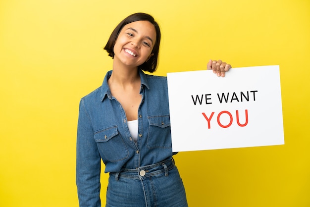 Jeune métisse femme isolée sur fond jaune tenant Nous voulons que vous embarquiez avec une expression heureuse