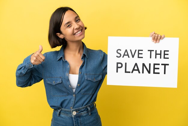 Jeune métisse femme isolée sur fond jaune tenant une pancarte avec texte Save the Planet avec le pouce vers le haut