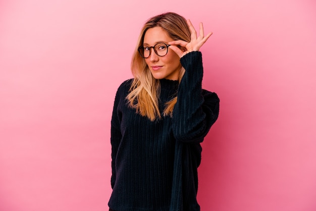 Jeune métisse femme isolée sur rose excité en gardant le geste ok sur les yeux.