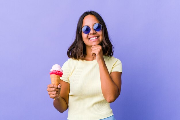 Jeune métisse femme mangeant une glace souriant heureux et confiant, touchant le menton avec la main.