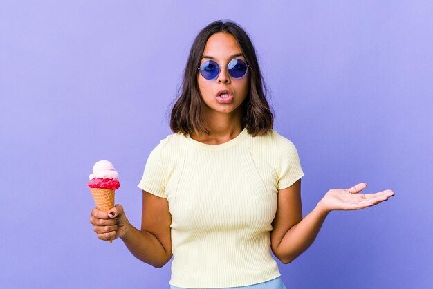 Jeune métisse femme mangeant une glace surprise et choquée.