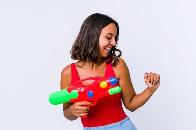 Jeune métisse femme tenant un pistolet à eau isolé danser et s'amuser.