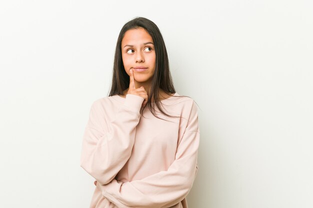 Jeune mignon adolescent hispanique femme regardant de côté avec une expression douteuse et sceptique