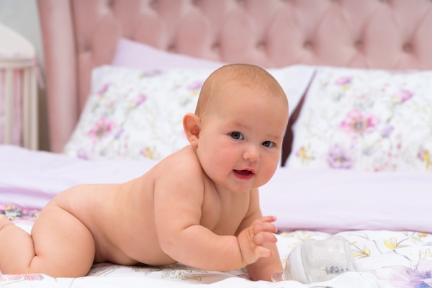 Jeune mignon petit bébé rampant dans son lit, vu de côté et regardant la caméra