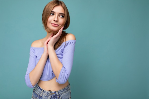 Jeune mignonne heureuse belle femme blonde foncée avec des émotions sincères isolées sur le mur de fond avec