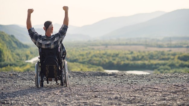 Jeune militaire à la retraite dans un fauteuil roulant profitant de l'air frais lors d'une journée ensoleillée sur la montagne