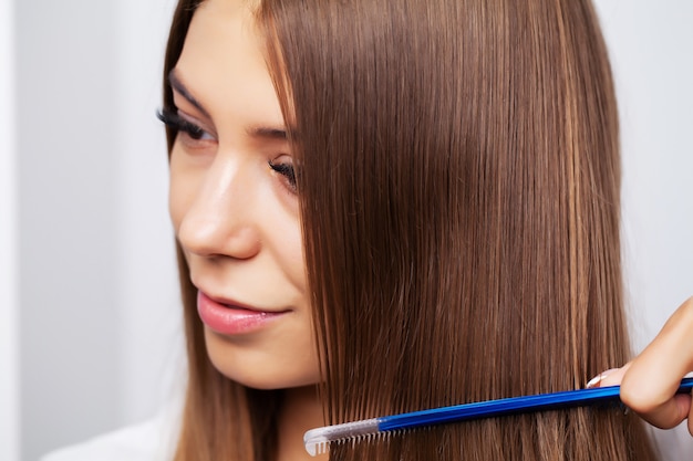 Jeune modèle féminin avec de beaux cheveux longs peigne son peigne