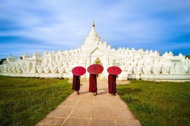 Jeune moine asiatique tenant des parapluies rouges sur la pagode Mya Thein Tan à Mingun, Mandalay