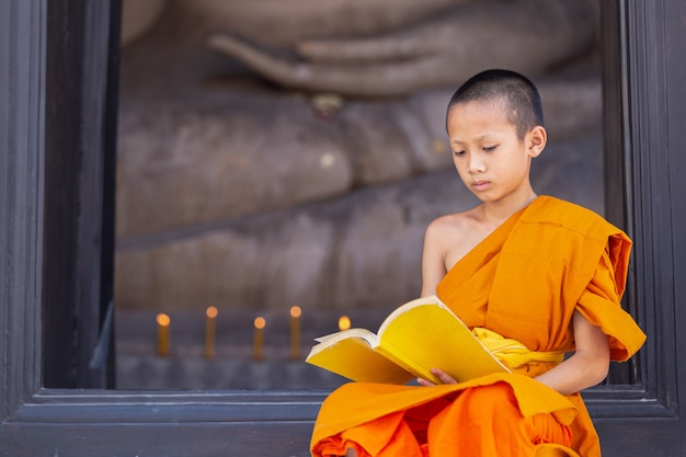 Jeune moine novice lisant un livre dans le temple Wat Phutthai Sawan, Ayutthaya, Thaïlande