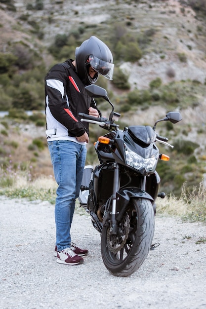 Jeune motard met sa veste avant de conduire sa moto.