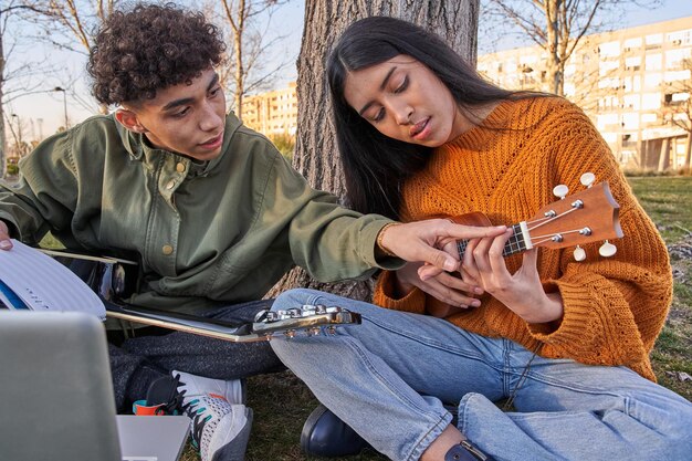 Jeune musicien apprenant à une belle femme latine aux cheveux longs à jouer du ukulélé