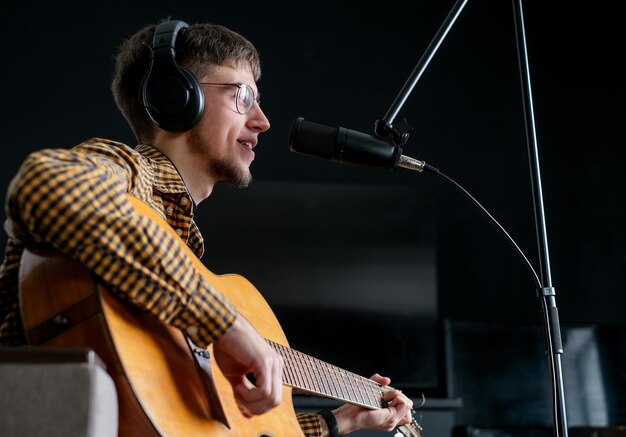 Un jeune musicien chante une chanson en jouant de la guitare classique dans un studio de musique.