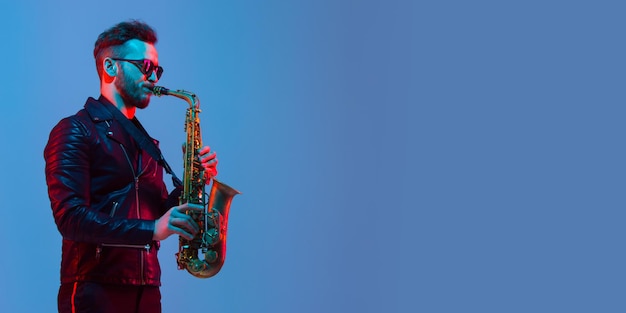 Jeune musicien de jazz caucasien jouant du saxophone à la lumière au néon, flyer