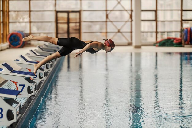 Une jeune nageuse plonge et saute dans la piscine pendant son entraînement