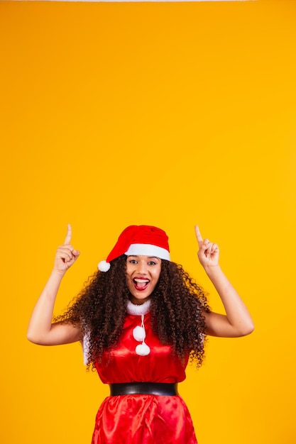 Photo jeune noelete habillée pour noël pointant vers un espace libre pour le texte.