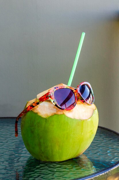 Une jeune noix de coco prête à manger sur une table en verre pour le concept de boisson d'été