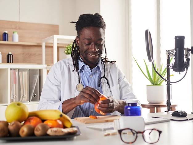 Un jeune nutritionniste fait une pause au bureau et mange une mandarine