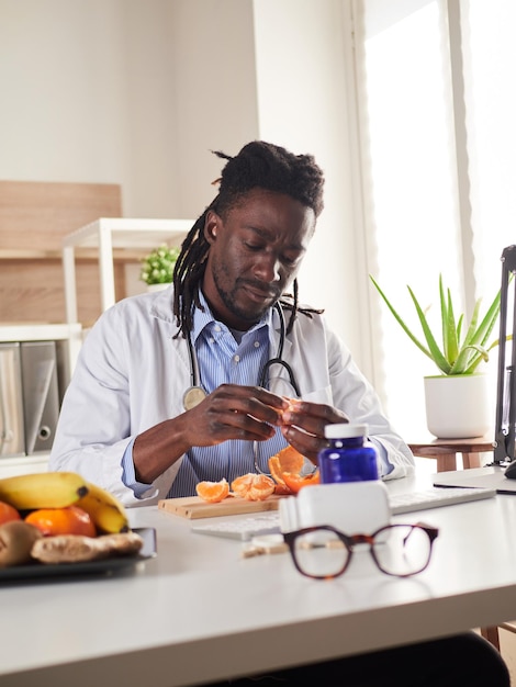 Un jeune nutritionniste fait une pause au bureau et mange une mandarine