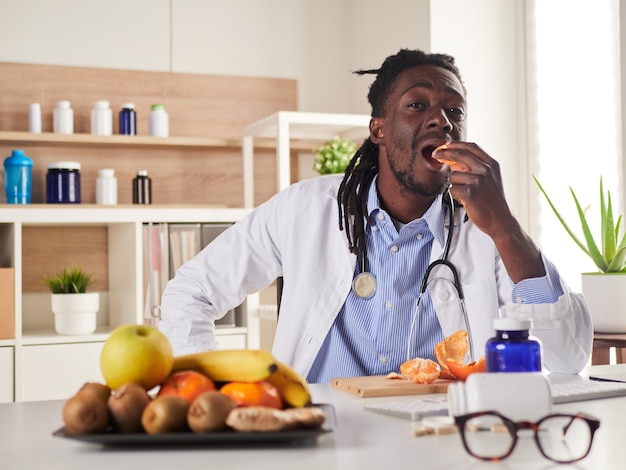 Un jeune nutritionniste fait une pause au bureau et mange une mandarine