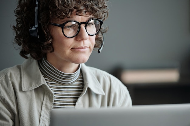 Jeune opératrice brune sérieuse dans le casque et les lunettes