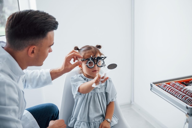 Photo le jeune ophtalmologiste est avec une petite visiteuse à la clinique.