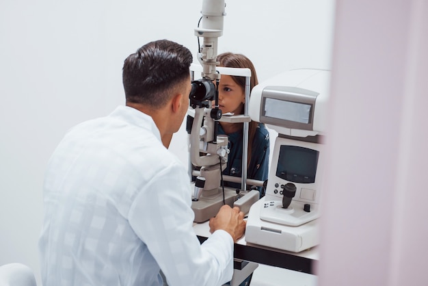 Le jeune ophtalmologiste est avec une petite visiteuse à la clinique.