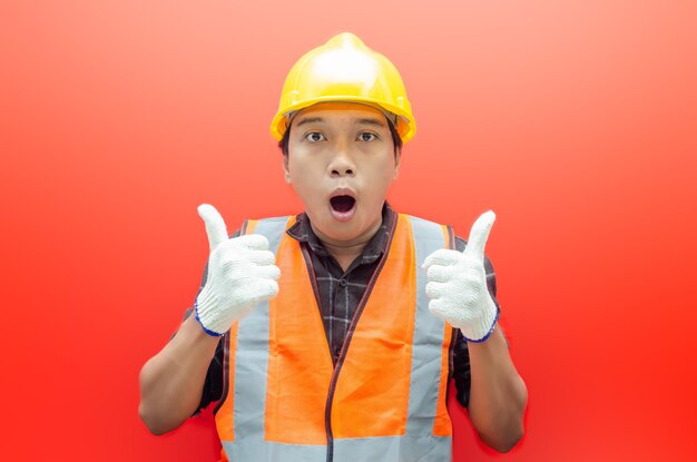 Jeune ouvrier du bâtiment asiatique ou ingénieur souriant joyeusement et donnant le pouce en l'air en guise de compliment.