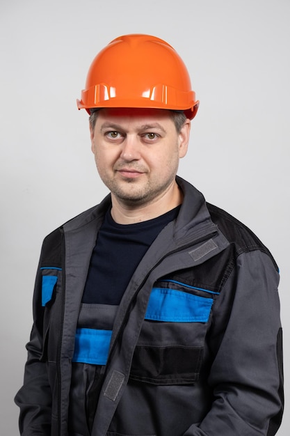 Un jeune ouvrier du bâtiment portant un casque de sécurité et un uniforme de travail sur fond blanc