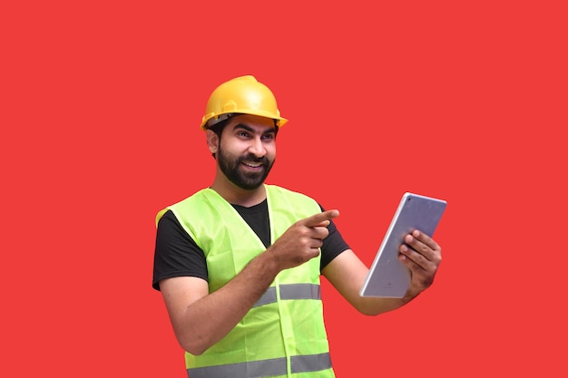 jeune ouvrier du bâtiment souriant tenant l'onglet et pointant vers la gauche modèle pakistanais indien