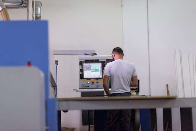 Le jeune ouvrier travaille dans une usine pour la production des meubles en bois