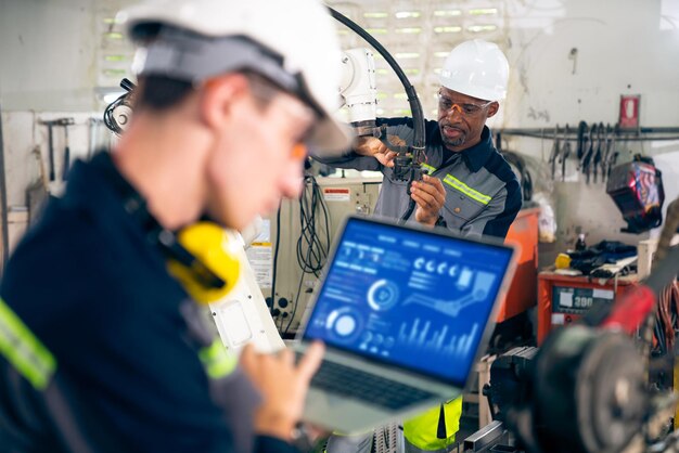 Photo jeune ouvrier d'usine travaillant avec un bras robotique adepte