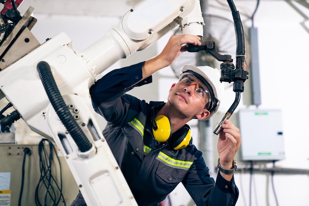 Jeune ouvrier d'usine travaillant avec un bras robotique adepte