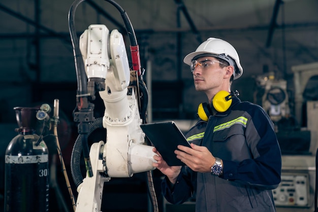 Jeune ouvrier d'usine travaillant avec un bras robotique adepte