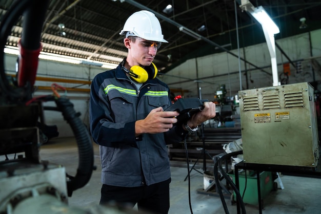 Jeune ouvrier d'usine travaillant avec un bras robotique adepte