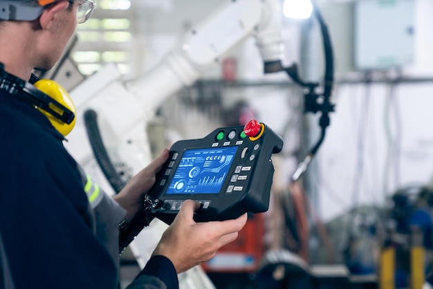 Jeune ouvrier d'usine travaillant avec un bras robotique adepte