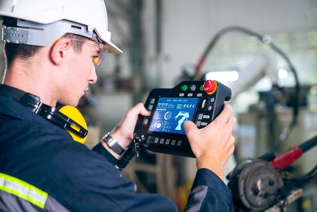 Jeune ouvrier d'usine travaillant avec un bras robotique adepte