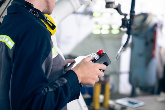 Jeune ouvrier d'usine travaillant avec un bras robotique adepte