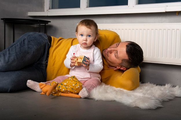 Jeune papa avec sa fille mignonne et heureuse sur fond noir. Père et petite fille d'un an.